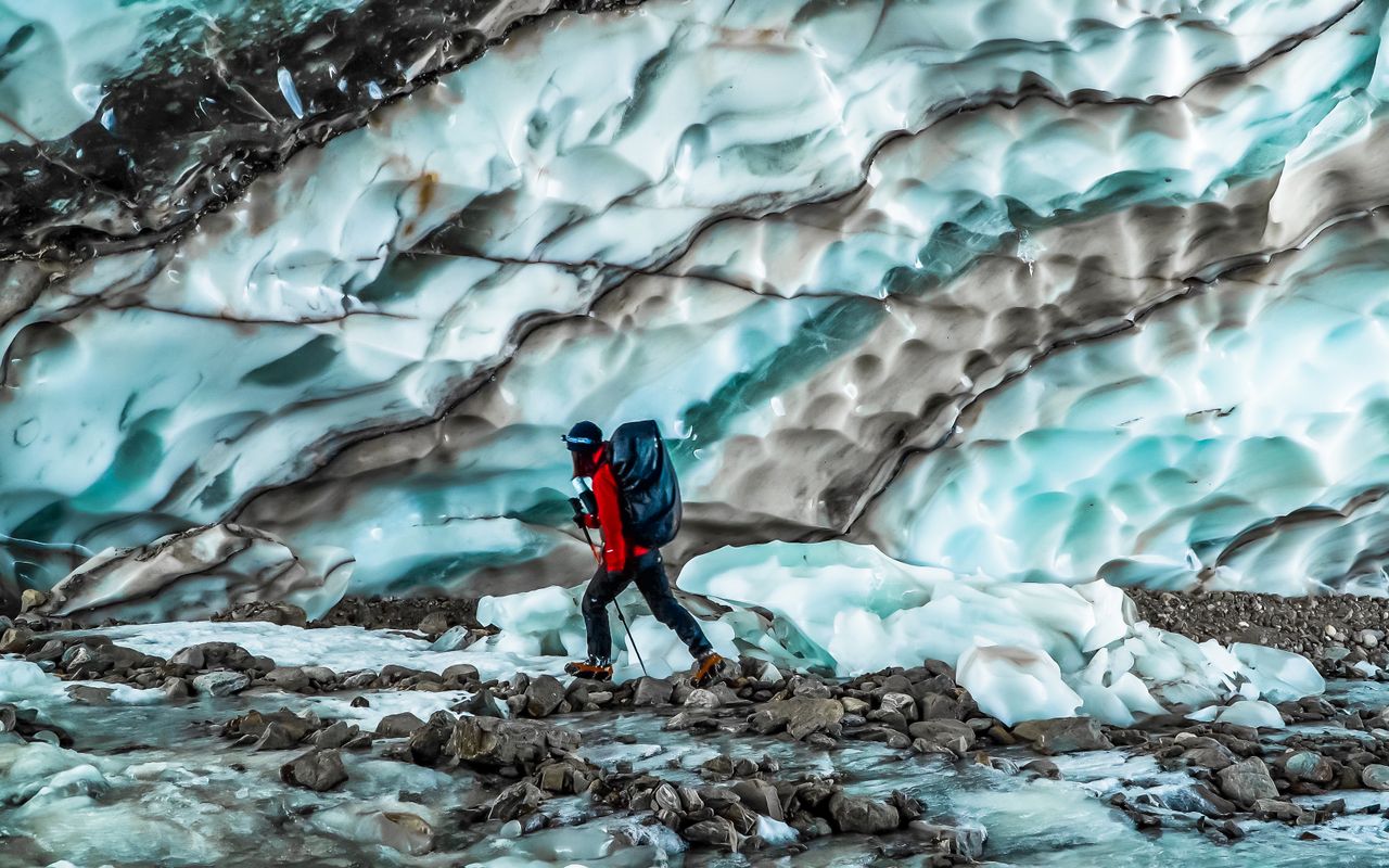 services-02 A lone hiker treks through a stunning glacier landscape in Yunnan, China, capturing natures beauty.
